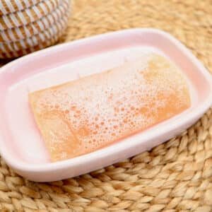 savon à.froid surgras à l'huile d'amande douce posé sur un porte-savon avec sa mousse